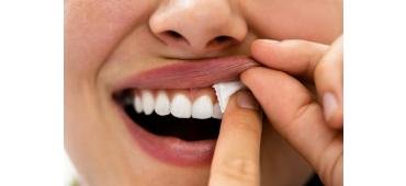 A beautiful white woman showing how a nicotine pouch is placed under the upper lip